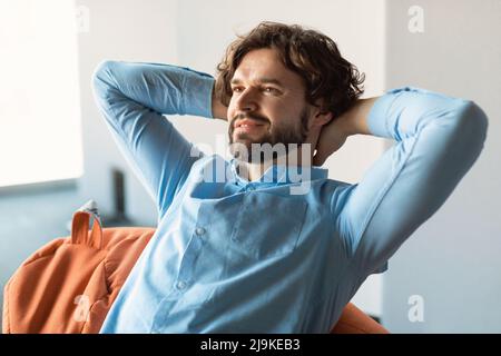 Smiling middle aged man sitting on beanbag and thinking Stock Photo