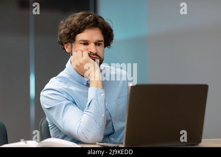 Bired business man leaning head on hand using pc Stock Photo