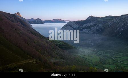 Landscape at dawn where we see the mountains and the valley of the Somiedo Natural Park in Asturias, Spain, with low clouds or mist in the green valle Stock Photo