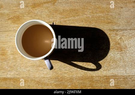 mug of coffee on weathered table top with long shadow Stock Photo