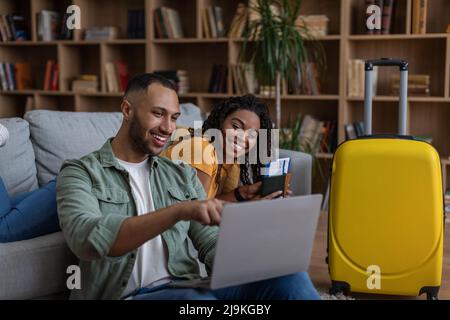 Happy young black couple using laptop and searching place for travel, getting ready for honeymoon holiday trip concept Stock Photo