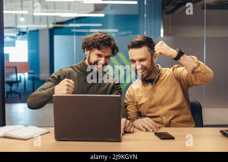 Triumphant coworkers celebrating business achievement or success, making great deal, looking at laptop screen at office Stock Photo