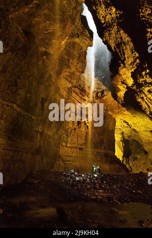 Inside the vast main cavern of Gaping Gill pothole, Ingleborough, Yorkshire Dales National Park, UK. A caver is seen descending on a rope. Stock Photo