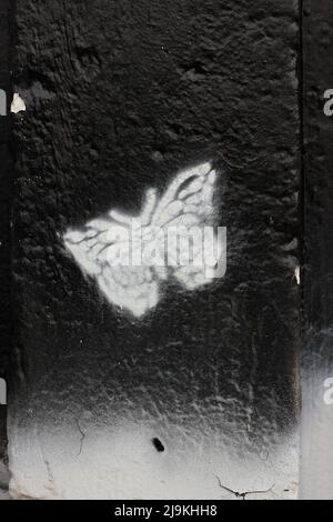 Beautiful monarch butterfly fluttering about while painted on a city wall. Stock Photo