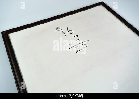 Addition calculation with black color marker on whiteboard, math idea, primary school, learning mathematic concept, white school board, sitting view Stock Photo