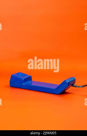 Antique blue corded telephone on an orange background. Stock Photo