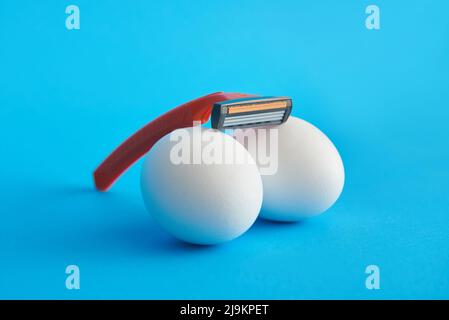 Razor blade on white eggs, intimate depilation concept Stock Photo
