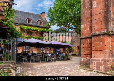 Collonges-la-Rouge, France - 13 May, 2022: tourists enjoy a drink and meal in a quaint restaurant in the red sandstone village of Collonges-la-Rouge Stock Photo