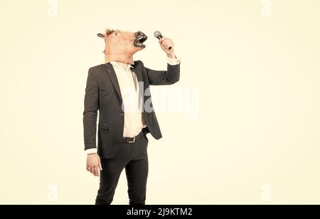 Professional man wear horse head mask in formalwear singing karaoke song, costume party Stock Photo