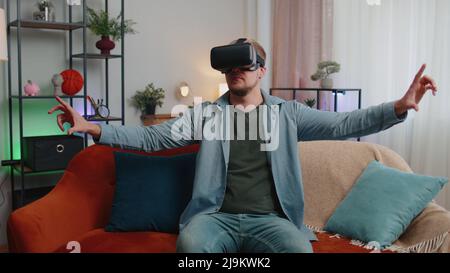 Adult man use virtual reality headset glasses at home, enjoying video concept moving hands in air Stock Photo