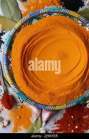 Colorful still life with turmeric powder on blue handmade plate. Close up photo of different spices on light grey background. Stock Photo