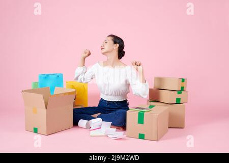 Woman is stretching while preparing products in the packaging box to prepare for delivery to customers. Stock Photo
