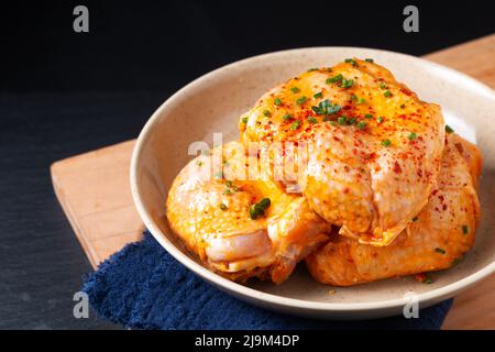 Food concept homemade spicy chicken thighs marinade in ceramic bowl on wooden board with black background and copy space Stock Photo
