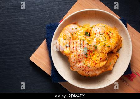 Food concept homemade spicy chicken thighs marinade in ceramic bowl on wooden board with black background and copy space Stock Photo