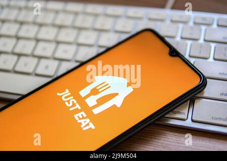 In this photo illustration, a Just Eat Takeaway logo seen displayed on a smartphone placed on top of a computer keyboard. Stock Photo