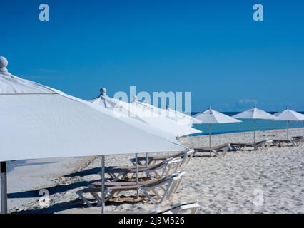 White sunbeds and umbrellas on a deserted tropical beach in Isla Mujeres, Mexico Stock Photo