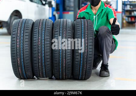 Auto Mechanic thumbs up with 4 new tires that change tires in the auto repair service center. Stock Photo