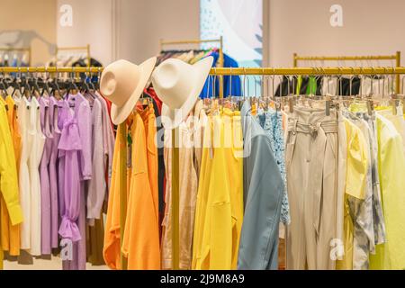 Multicolored youth clothes on hangers in shop, summer and spring assortment in clothing store Stock Photo