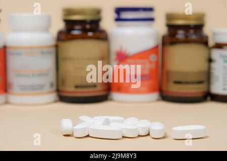 Medicines or dietary supplements on a beige background and jars with pills on the background. Stock Photo