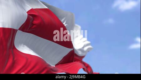 The flag of Greenland waving in the wind on a clear day. Greenland is the world's largest island, and one of the three constituent countries that form