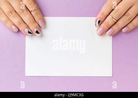 Close up womans hand with creative nail design holding postcard Stock Photo