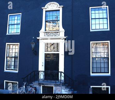 Facade of typical Dutch house with blue painted brick walls , steps, front door ,glass windows and bike in popular neighborhood street, Netherlands Stock Photo