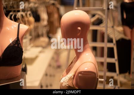 Mannequin of girl is viewed from side. Head without hair. Figure of man made of plastic. Details of clothing store. Stock Photo