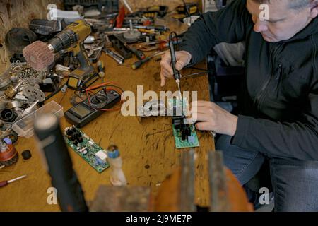 Close up of repairman is soldering circuit board of electronic device on the table Stock Photo