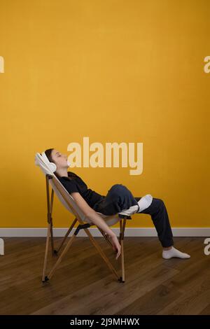 Side view of anonymous ethnic male freelancer in black polo leaning on wall and working remotely on modern laptop while on city street Stock Photo
