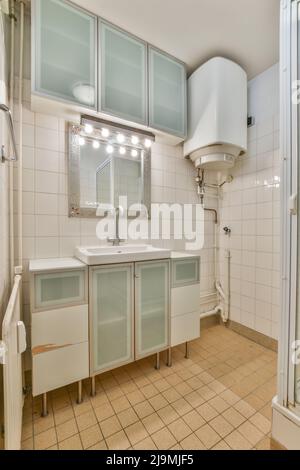 Sink and cabinets placed in tiled wall in bathroom Stock Photo