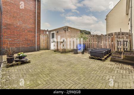Tiled floor on backyard of building with wooden fence and green plants in rural area Stock Photo