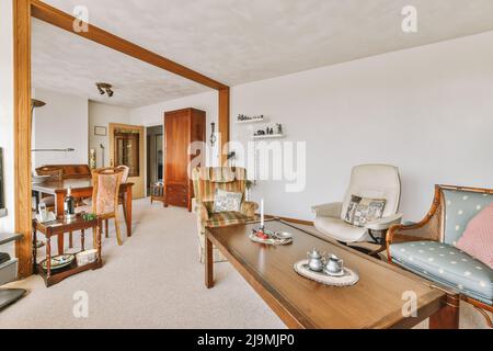 Table placed in vintage dining room and living room of apartment with coffee table and armchair Stock Photo