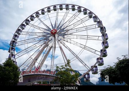 View of a giant Ferris wheel at the Hohematte park in Interlaken , Switzerland , set against a blue cloudy sky. Stock Photo