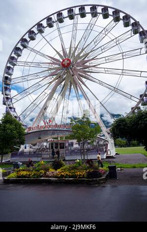 View of a giant Ferris wheel at the Hohematte park in Interlaken , Switzerland , set against a blue cloudy sky. Stock Photo