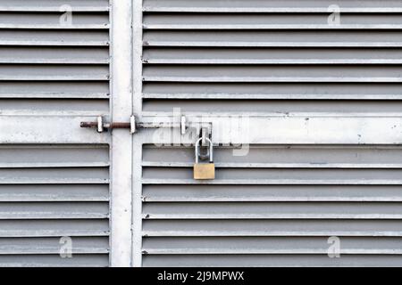 Small padlock hanging on closed metal doors Stock Photo