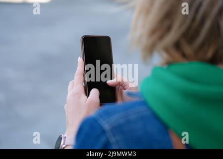 Woman holds smartphone in hands on street closeup Stock Photo