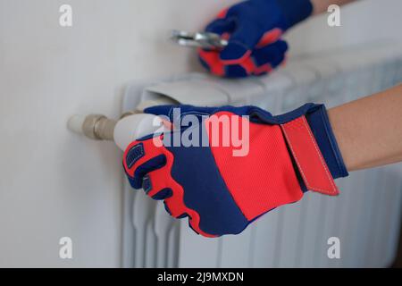 Plumber adjusts heating system in radiators of house Stock Photo