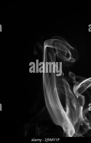 A black and white swirling, ascending smoke pattern on a black background, photo could be used as a background, smoke texture, abstract, or general st Stock Photo