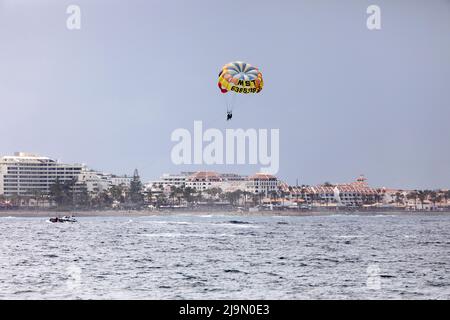 People at parasailing over the sea at Playa de las Américas in Tenerife, Spain. The area is a popular tourism destination.. Stock Photo