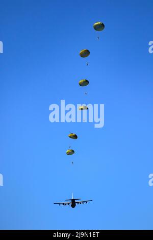 Military parachutist paratroopers parachute jumping out of a air force planes on a clear blue sky day. Stock Photo