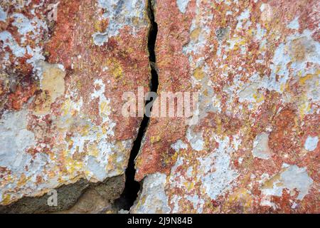 Big deep crack on old plastered colorful wall. Remains of colored plaster. Numerous layers of paint. Copy space. Close-up. Selective focus. Stock Photo