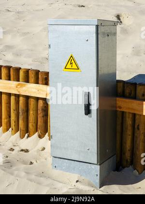 New galvanized metal outdoor electrical power supply and distribution cabinet on a sandy beach Stock Photo