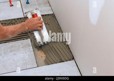 Bathroom renovation on the applying tile adhesive to the floor Stock Photo