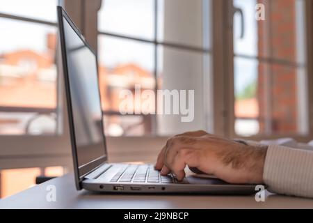 Man working on a laptop in his house with large windows of light. Stock Photo