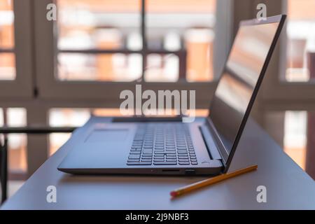 Laptop in a house with large windows prepared for teleworking. Stock Photo