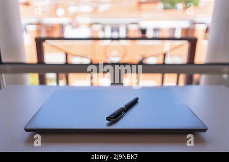 Laptop in a house with large windows prepared for teleworking. Stock Photo