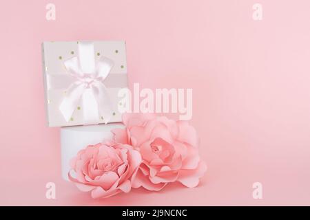 White circular pedestal with gift box and paper rose ornament. Copy space. Stock Photo