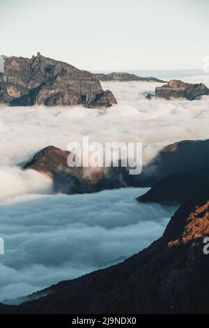View on highest rocky mountains of the island of Madeira emerge from the clouds into the sunset from the viewpoint of Pico Ruivo do Paul. Beauty of th Stock Photo