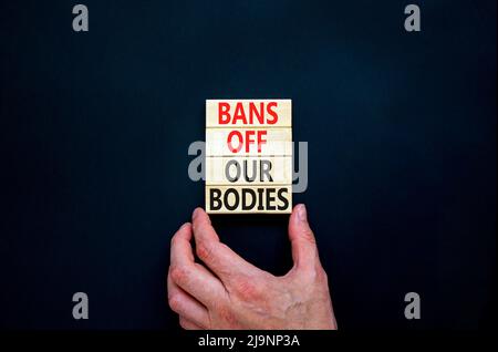 Bans off our bodies symbol. Concept words Bans off our bodies on wooden blocks on beautiful black table black background. Women rights concept. Busine Stock Photo