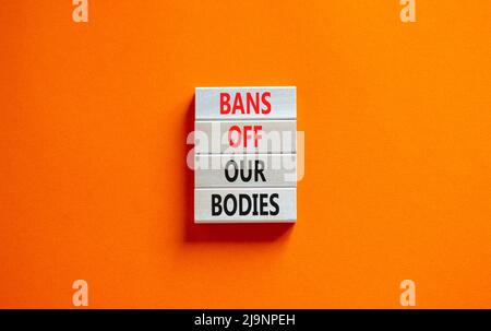 Bans off our bodies symbol. Concept words Bans off our bodies on wooden blocks on beautiful orange table orange background. Women rights concept. Busi Stock Photo